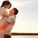 Man lifting woman during a sunset over the ocean